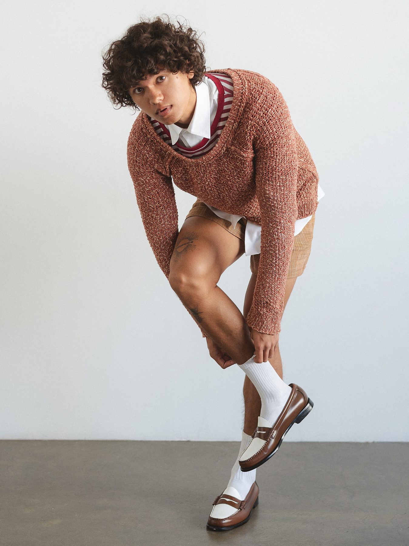 Quentin Lee in rust knit sweater and loafers, full body editorial